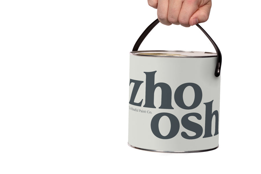 A hand holds a tin of Zhoosh paint