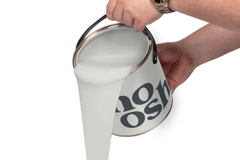 A person pours Mellow Grey paint from a tin