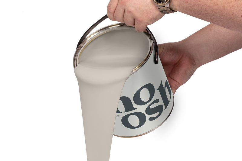 A person pours World Grey paint from a tin